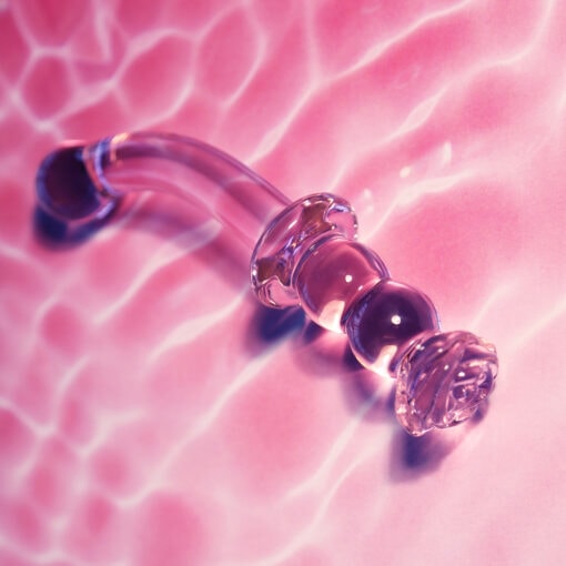 A glass pipe laying on top of a pink surface.