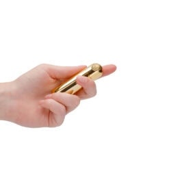 A close-up of a hand holding a sleek, gold-colored vibrator designed for adult pleasure, emphasizing luxury, innovation, and sexual wellness.