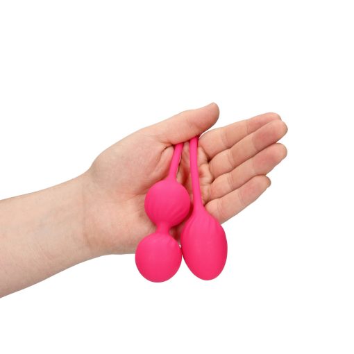 Two pink balls in a person's hand.