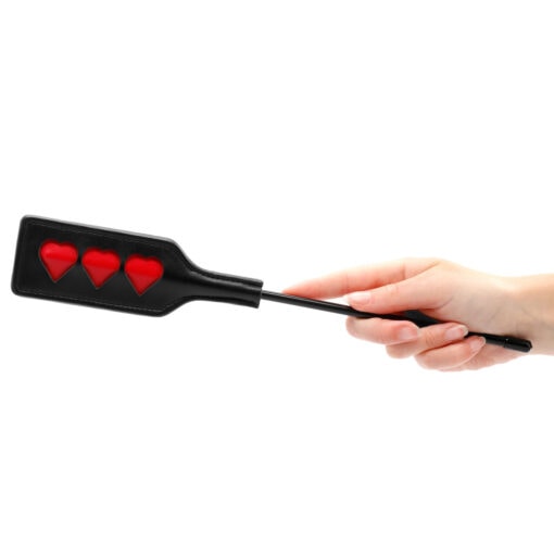 A woman's hand holding a paddle with red hearts on it.