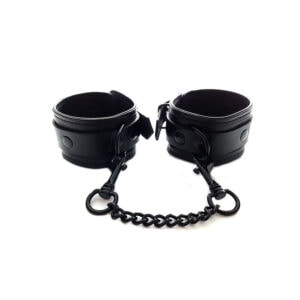 A pair of black leather cuffs on a chain.