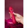 A hand holding a red vibrator with roses on it.