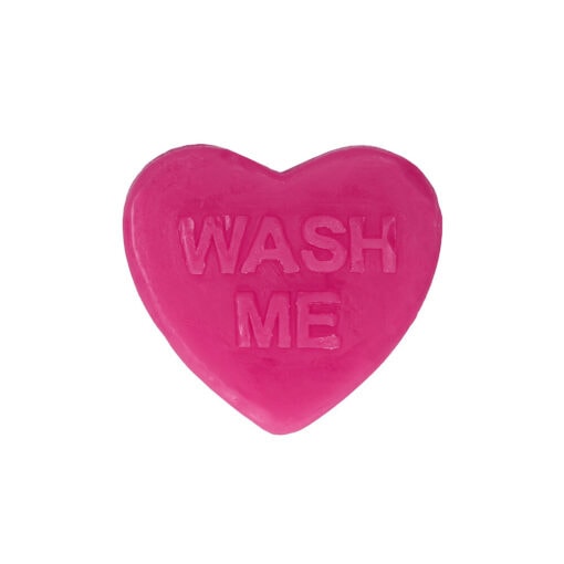 A pink heart shaped soap that says wash me.