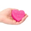 A hand holding a pink heart soap with the word wash me on it.