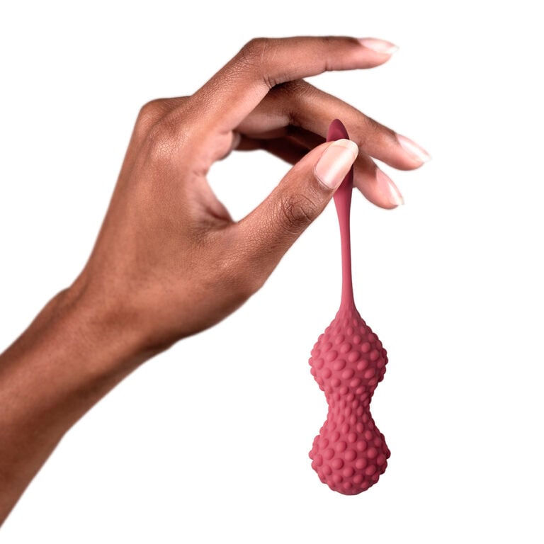 Close-up of a hand holding a pink silicone Kegel exercise toy with textured surface, designed for pelvic floor strengthening and sexual wellness enhancement.