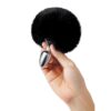 A person holding a black furry ball in their hand.