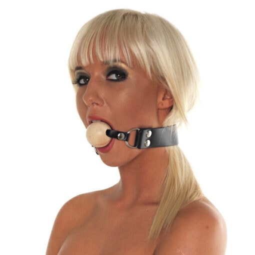 A woman is holding a wooden ball in her mouth.