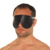A man wearing a black leather eye mask.